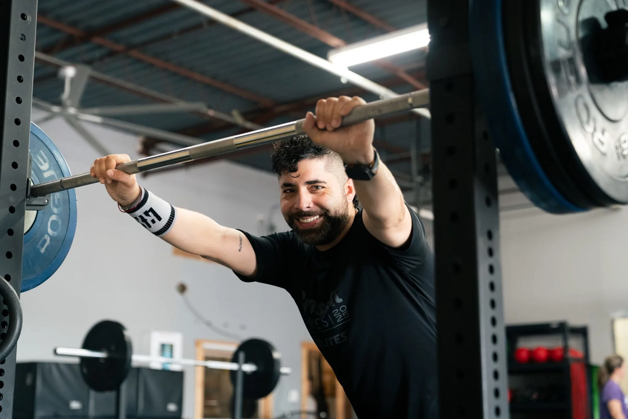 A REP member smiling under the barbell during a coached class